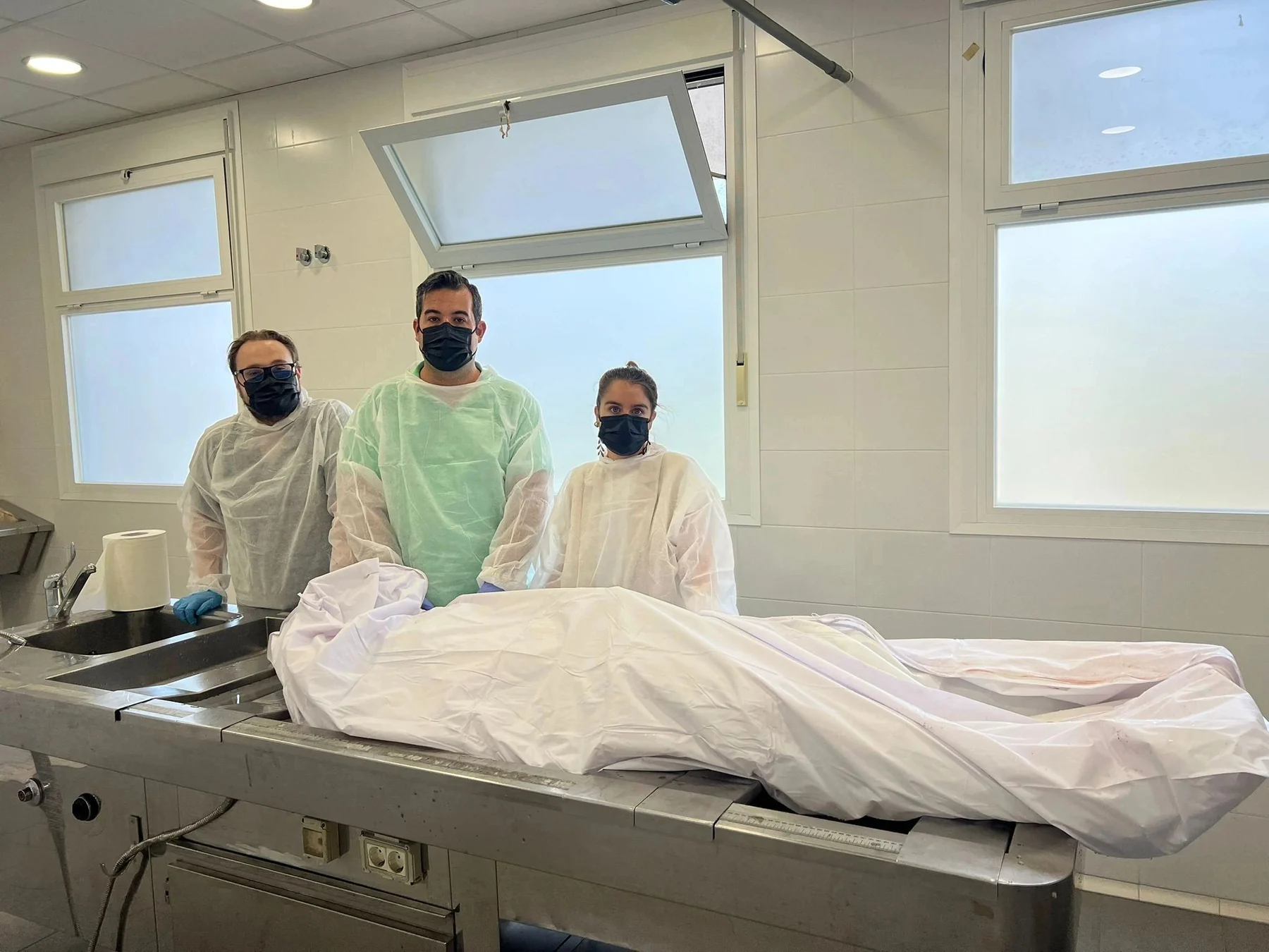 Equipo forense en una sala de autopsias durante un examen post mortem